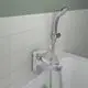 Chromene Badearmatur von Ideal Standard mit Handbrause, montiert an der Wand über einer weißen Badewanne, auf hellen Fliesen.